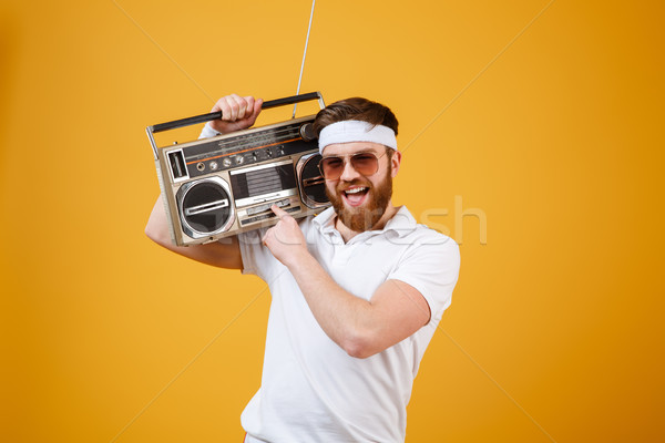 Happy young man wearing sunglasses holding tape recorder Stock photo © deandrobot