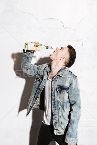 Attractive man standing on floor drinking alcohol Stock photo © deandrobot