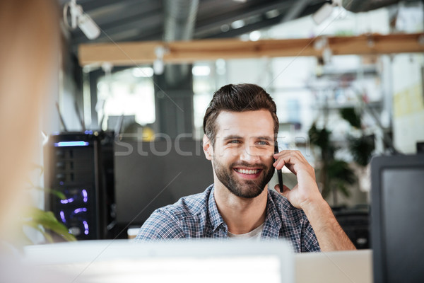Man in office coworking while talking by mobile phone. Stock photo © deandrobot