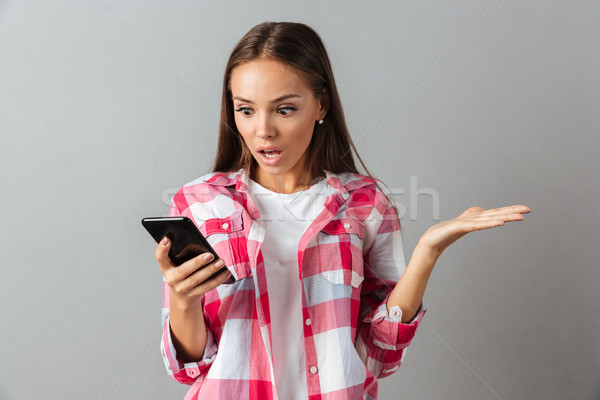 Portrait of a shocked pretty woman in plaid shirt Stock photo © deandrobot