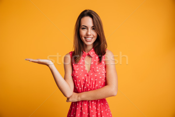 Smiling brunette woman in dress holding copyspace on the pound Stock photo © deandrobot