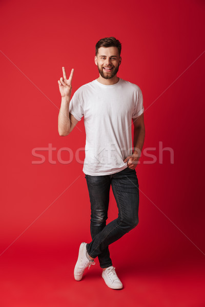 Happy young man standing isolated showing peace gesture. Stock photo © deandrobot