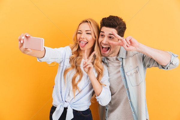 Portrait of funny man and woman taking selfie photo on mobile ph Stock photo © deandrobot