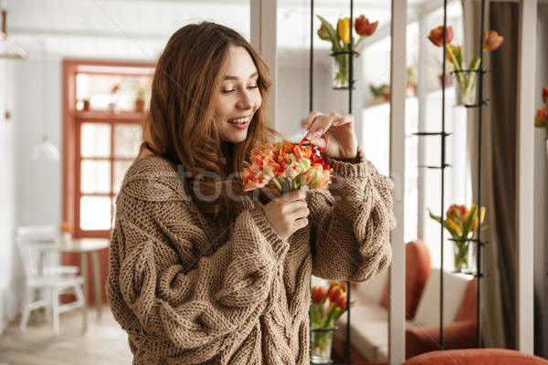 Photo of lovely woman in knitted sweater, holding amazing flower Stock photo © deandrobot
