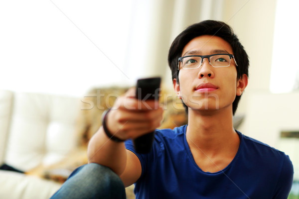 Serious man sitting on couch watching tv at home in the living room Stock photo © deandrobot