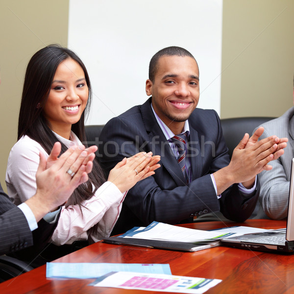 Multi ethnic business group greets you with clapping and smiling. Focus on woman Stock photo © deandrobot