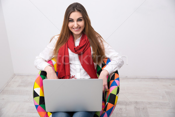 Stok fotoğraf: Gülümseyen · kadın · oturma · renkli · sandalye · dizüstü · bilgisayar · ofis