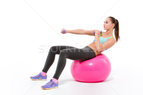Woman doing exercises with dumbbells on fitness bal Stock photo © deandrobot