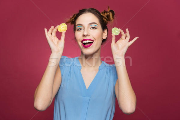 Cheerful beautiful young woman smiling and holding jelly candies  Stock photo © deandrobot