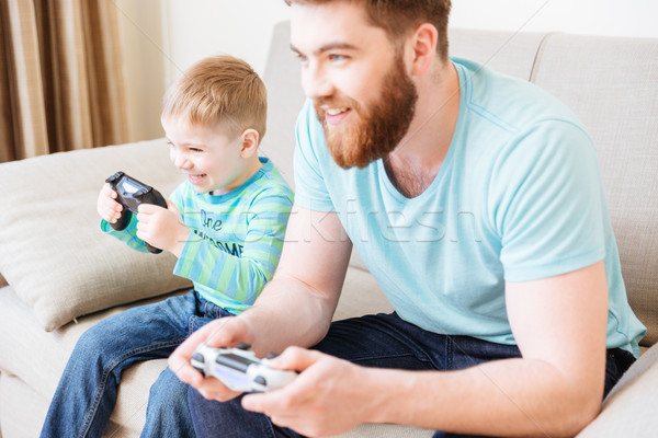 Stock photo: Little son and dad playing computer games at home together 