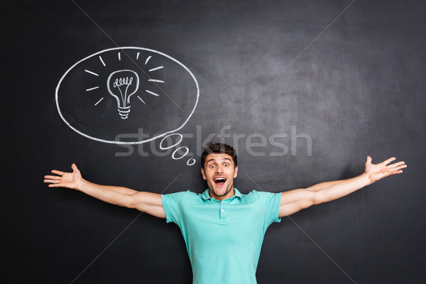 Happy excited young man with raised hands having an idea Stock photo © deandrobot