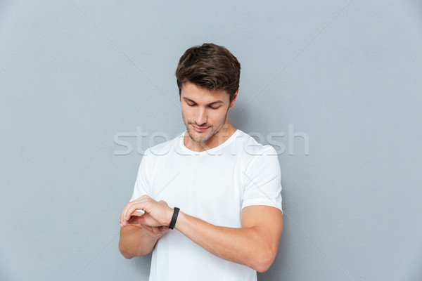 Serious young man standing and checking fitness tracker Stock photo © deandrobot