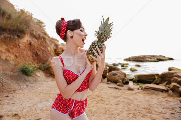Mosolyog pinup lány tart ananász tengerpart Stock fotó © deandrobot