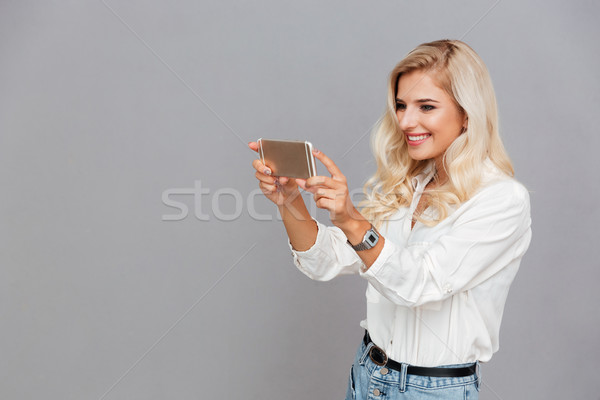 Beautiful young girl making photo on smartphone Stock photo © deandrobot