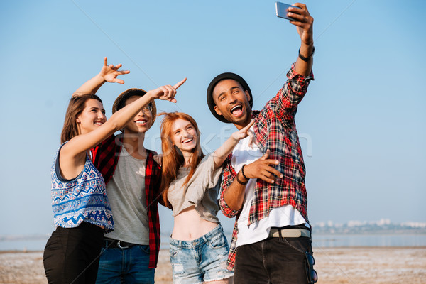 Stock photo: Group of cheerful friends taking selfie with mobile phone outdoors