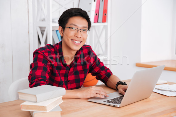 Student looking on camera and working at laptop in classroom Stock photo © deandrobot