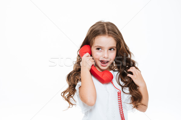 Portrait of pretty curly little girl talking on red telephone Stock photo © deandrobot