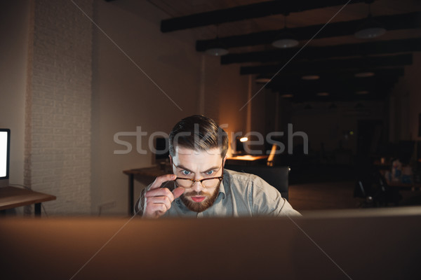 Confused web designer working at night and looking to computer. Stock photo © deandrobot