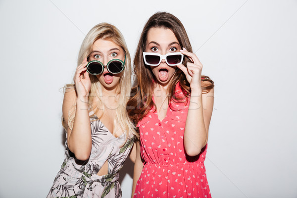 Portrait of attractive shocked women looking at camera through eyeglasses Stock photo © deandrobot