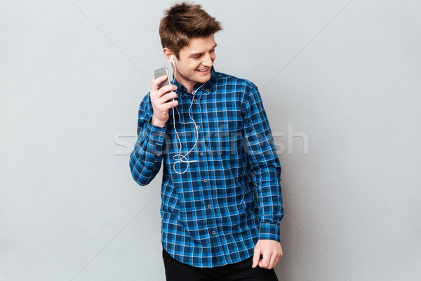 Young man looking away while listening music Stock photo © deandrobot