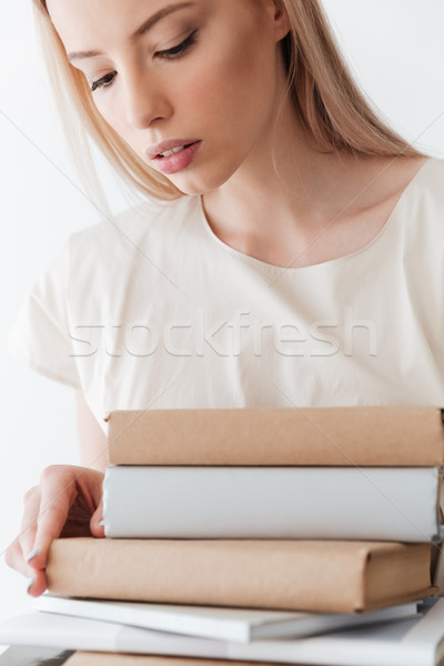 Serious blonde woman holding books. Looking aside. Stock photo © deandrobot