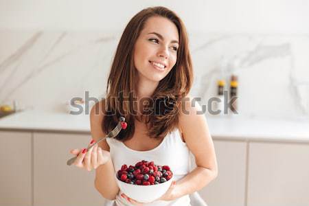Young woman eating healthy food in kitchen Stock photo © deandrobot