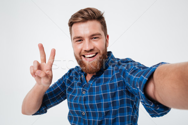 Smiling bearded man in checkered shirt making selfie Stock photo © deandrobot