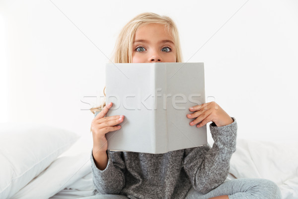 Close-up portrait of charming girl covering her face with book,  Stock photo © deandrobot