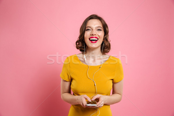 Portrait of a smiling woman in earphones listening to music Stock photo © deandrobot