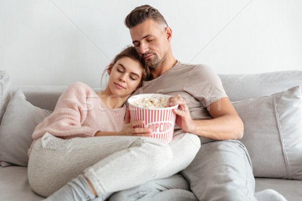 Pretty loving couple sitting on couch together with popcorn Stock photo © deandrobot