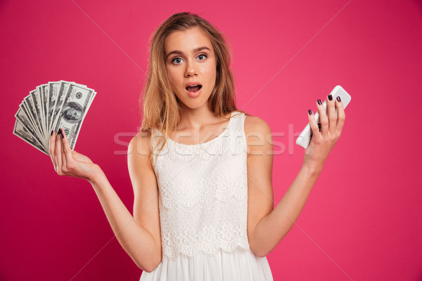 Portrait of an astonished pretty girl showing money banknotes Stock photo © deandrobot