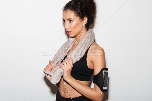 Serious curly brunette fitness woman with towel listening music Stock photo © deandrobot