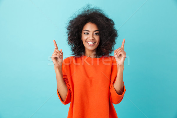 Optimistic american woman in colorful shirt looking on camera an Stock photo © deandrobot