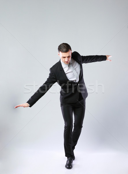 Businessman walking on invisible rope over gray background Stock photo © deandrobot