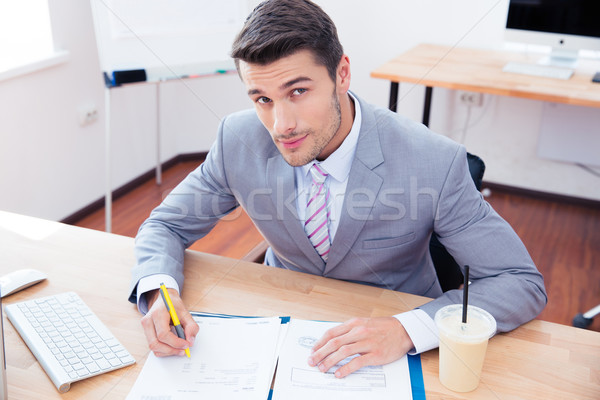 Handsome businessman signing document Stock photo © deandrobot