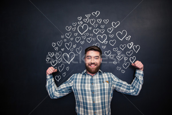 Happy man showing biceps and standing on blackboard background Stock photo © deandrobot