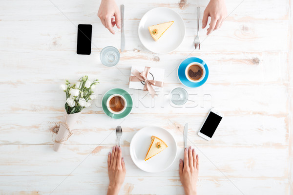 Hands of couple eating cakes and drinking coffee on table Stock photo © deandrobot
