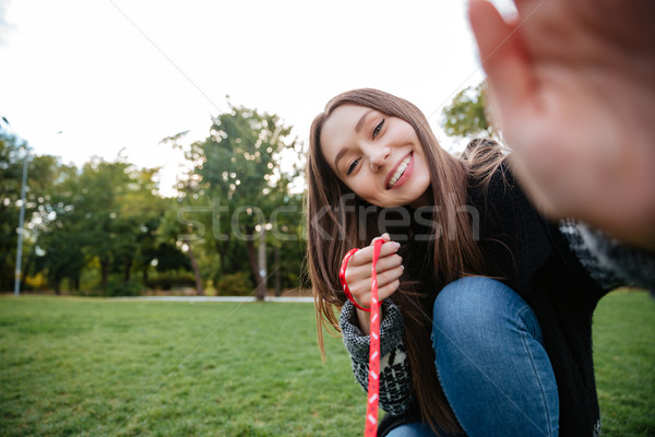 Smiling woman taking care of dog on leash in park Stock photo © deandrobot
