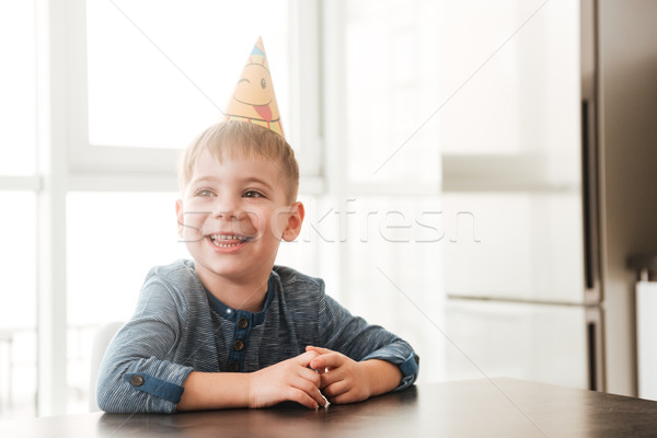 Cheerful birthday boy sitting in kitchen while smiling Stock photo © deandrobot