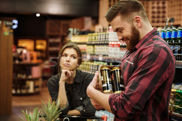 Loving couple in supermarket. Woman looking man holding beer. Stock photo © deandrobot