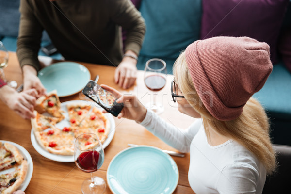 Friends sitting in cafe make photo of pizza Stock photo © deandrobot