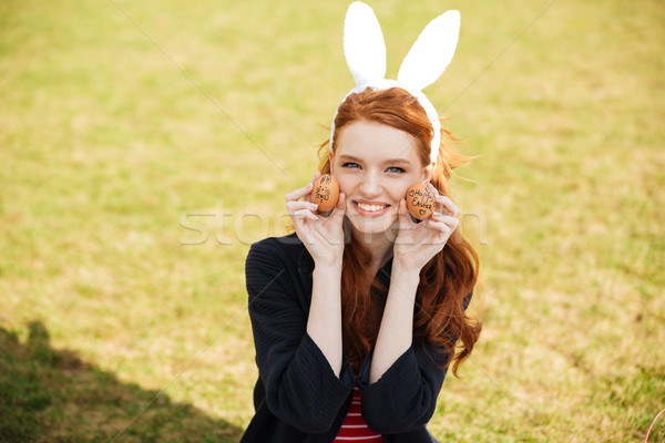 Portrait of a smiling red head woman wearing bunny ears Stock photo © deandrobot