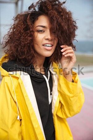 Amazing african curly young lady wearing yellow coat Stock photo © deandrobot