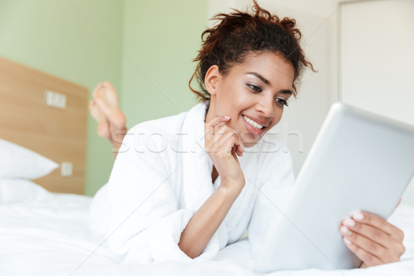 Stock photo: Happy young african woman lies on bed indoors