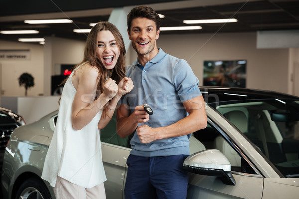 Lovng couple standing near car in car dealership. Stock photo © deandrobot