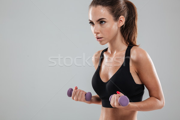 Vista lateral grave mujer ejercicio pesas Foto stock © deandrobot