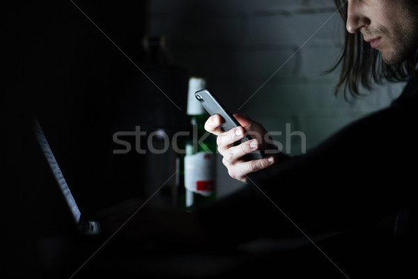 Concentrated man using laptop computer and mobile phone Stock photo © deandrobot