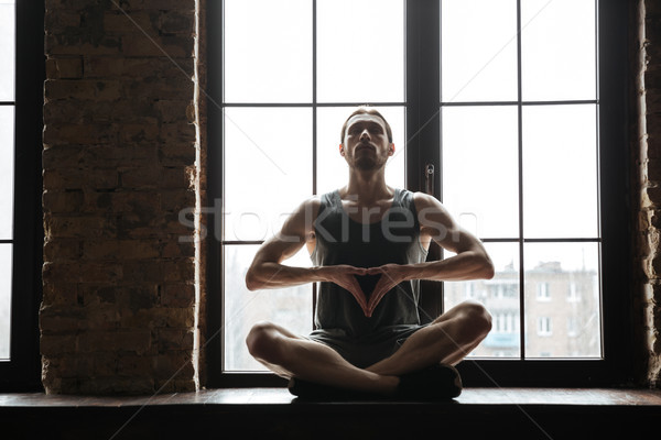 Portrait of a young concentrated sportsman meditating Stock photo © deandrobot