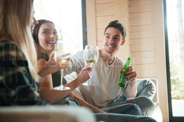 Cheerful young friends drinking wine and beer on sofa Stock photo © deandrobot