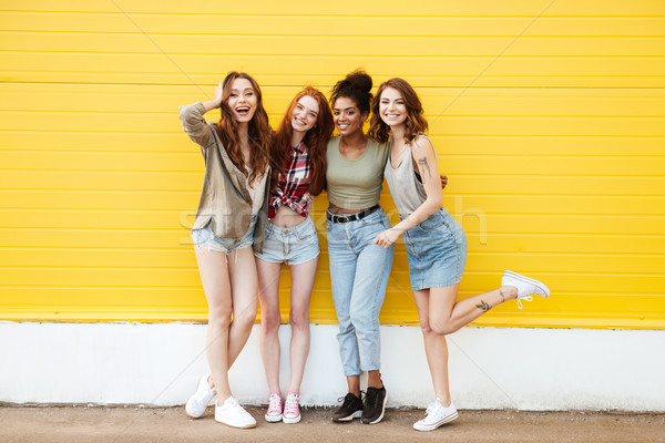 [[stock_photo]]: Souriant · femmes · amis · permanent · jaune · mur